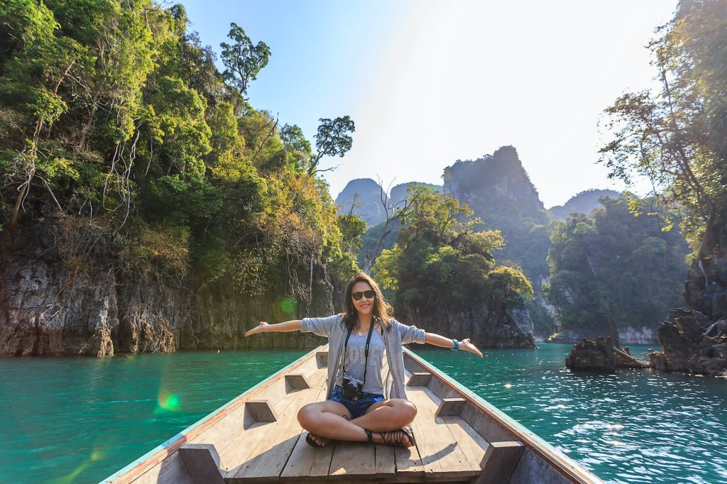 regenerative tourism photo of woman sitting on boat spreading her arms